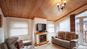 A cozy living room with a fireplace, a television, and two sofas. - A lodge that sleeps 4 guests  in 2 bedrooms (Windermere)