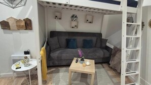 A compact living space with a sofa, a small table, and a ladder shelf. - Pretty Parisian studio (Paris)
