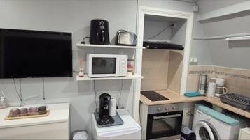 A compact kitchenette with a microwave, toaster, coffee maker, and a small oven.