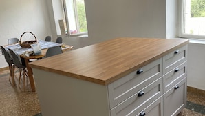 A kitchen with a wooden countertop, white cabinets, and a dining area with chairs and a table.