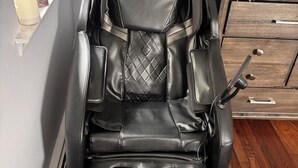 A massage chair in a room with a wooden floor, a small table with candles, and a cabinet with drawers. - Ryder Cup Rental, 1.4 miles away. 
3-bedroom apartment with parking (Farmingdale)