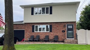 A two-story house with a garage, a brick facade, and a front porch with four Adirondack chairs. - Ryder Cup Rental, 1.4 miles away. 
3-bedroom apartment with parking (Farmingdale)