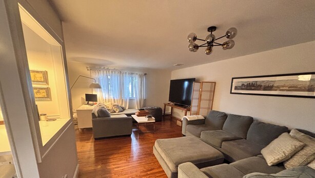 A modern living room with a grey sofa, a coffee table, and a TV. - Ryder Cup Rental, 1.4 miles away. 
3-bedroom apartment with parking (Farmingdale)