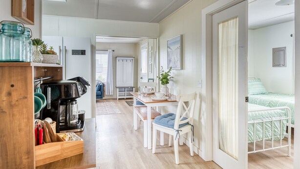 Una habitación acogedora con una mesa de madera, una silla blanca y una cama con edredón estampado en verde.