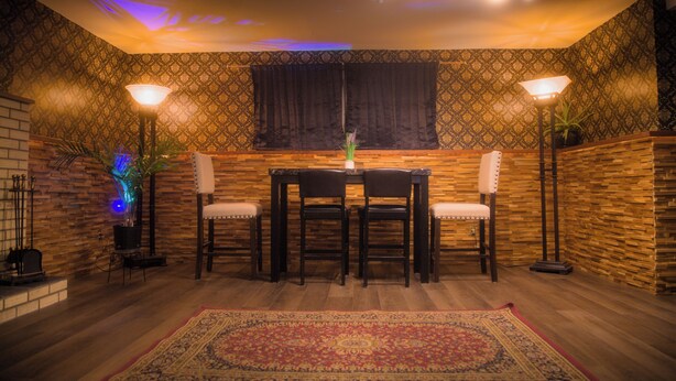 Ein Essbereich mit einem Holztisch, Stühlen, einer Wand mit Muster und einem dekorativen Teppich.