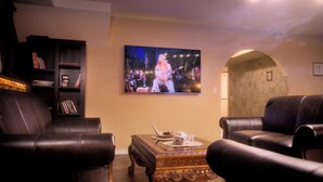 Ein Wohnzimmer mit Ledersofas, einem Couchtisch und einem Fernseher, der ein Konzert zeigt.