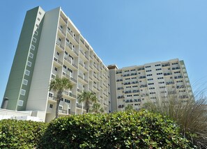 Ein mehrstöckiges Hotel mit Balkonen, einer flachen Dachfläche und blauem Himmel.
