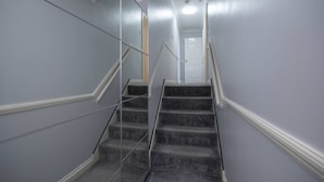 A staircase with carpeted steps and white handrails, leading to a door at the top. - in Bournemouth With 2 Bedrooms and 1 Bathrooms (Bournemouth)