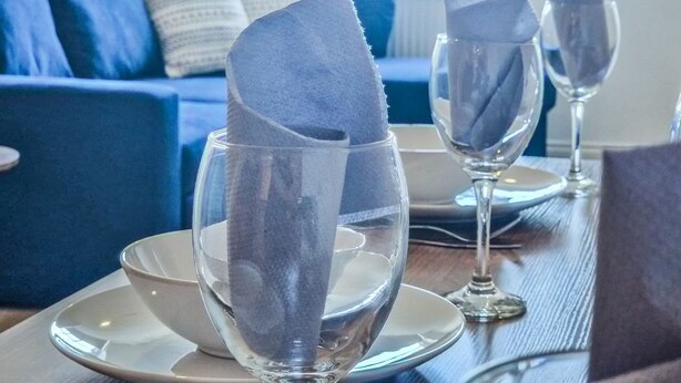 A dining table with three wine glasses, each with a folded napkin. - in Bournemouth With 2 Bedrooms and 1 Bathrooms (Bournemouth)