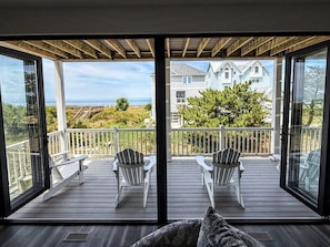 A balcony with two Adirondack chairs, a wooden deck, and a view of houses and the ocean. - Norfolk Family Beach House 5BR Walk To Sand • Ideal for Groups of 10! (Norfolk)