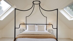 A four-poster bed in a room with sloped ceilings and skylights. - Beautifully presented dog friendly - The Coach House at Broadwell Manor (Broadwell)