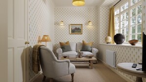 A cozy living room with a sofa, armchair, and a coffee table. There is a globe and a bowl on a window sill. - Beautifully presented dog friendly - The Coach House at Broadwell Manor (Broadwell)