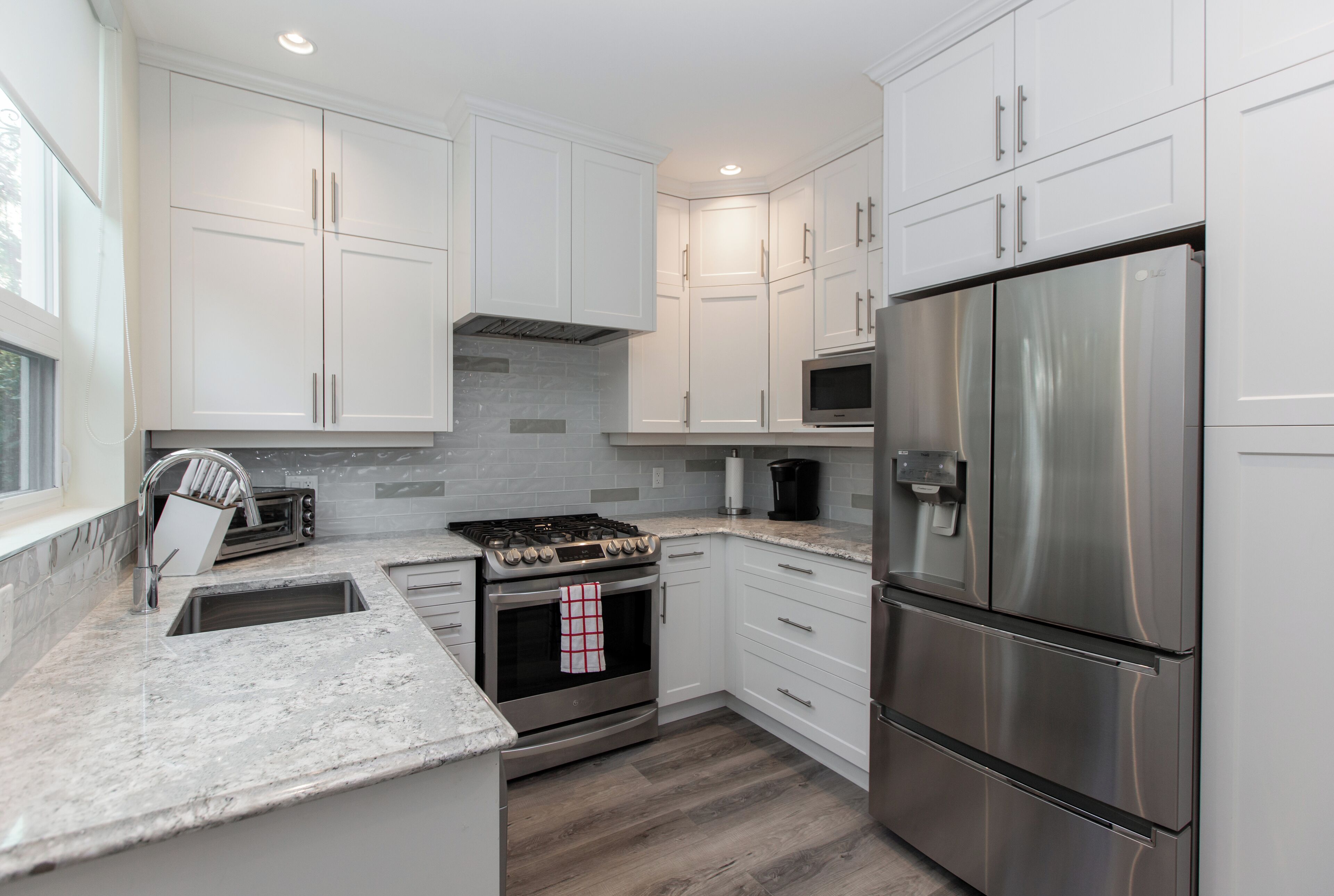 A modern kitchen with white cabinets, stainless steel appliances, and a granite countertop.