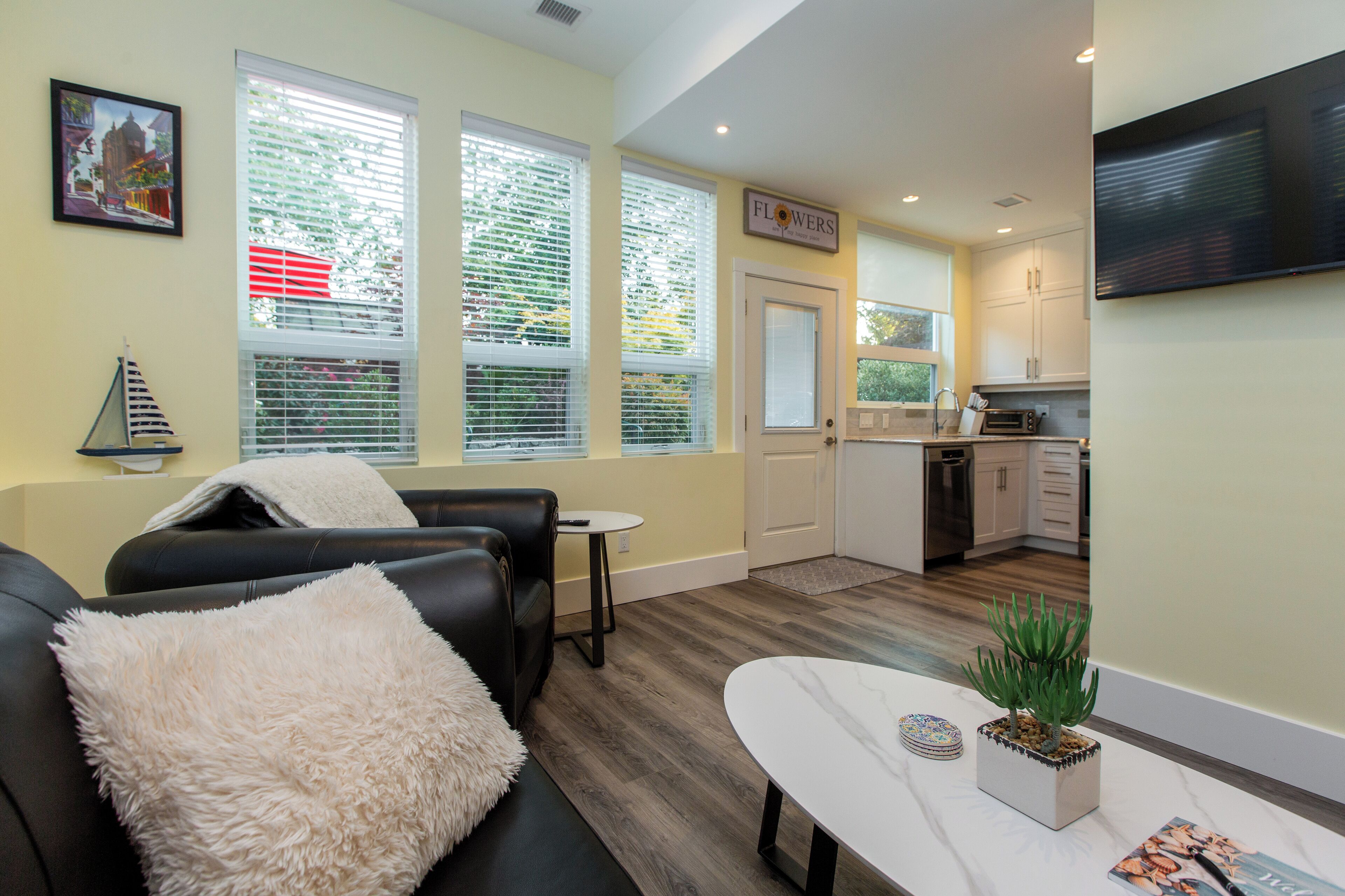 A modern living room with a sofa, a coffee table, and a small kitchen area in the background.