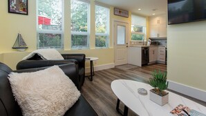 Un salon moderne avec un canapé, une table basse et un petit coin cuisine à l’arrière-plan.