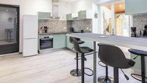 Een moderne keuken met een centraal eiland, barstoelen en een uitzicht op de stad door grote ramen.