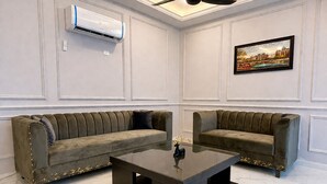 A room with two sofas, a coffee table, an air conditioner, and a painting on the wall. - Fantastic Spanish Villas In Heart Of Mirpur Azad Kashmir Pakistan (New Mirpur City)