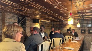 A group of people seated at a long wooden table in a restaurant with a brick wall and exposed ceiling lights. - The Inn at Southern Oaks located in Historic Lavonia, GA, close to Lake Hartwell (Lavonia)