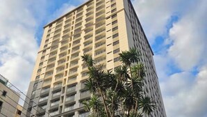 A tall, multi-story building with balconies and a tree in the foreground. - Stylish| 2 Beds| Fast Wifi| Best Area| (Nairobi)