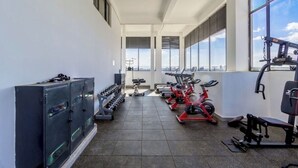 A gym with exercise equipment, a storage cabinet, and large windows offering a city view. - Stylish| 2 Beds| Fast Wifi| Best Area| (Nairobi)