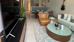 A modern living room with a flat-screen TV, a round coffee table, a sofa, and a dining area with a table and chairs. - Paradiso Caribe: Sea and Relax (María Chiquita)