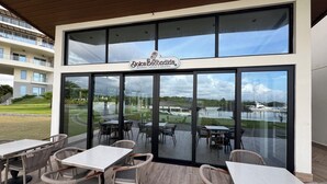 Un restaurante con terraza, amplias ventanas y vistas al puerto deportivo.