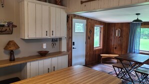 Un interior de madera con área de cocina, una mesa de comedor y un ventanal con cortinas.