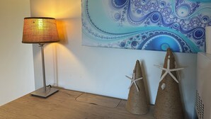 Una làmpada, dues estrelles de mar decoratives i un quadre abstracte blau a la paret.