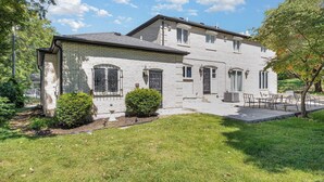 A two-story house with a brick exterior, a front porch, and a small front yard with a lawn and two bushes. - Spacious 4-bedroom house in Xenia near Universities (Xenia)