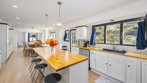 A modern kitchen with white cabinets, a wooden countertop, and a central island with bar stools. - Spacious 4-bedroom house in Xenia near Universities (Xenia)