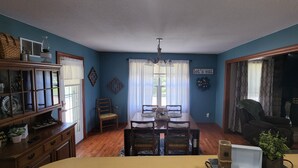 A dining area with a wooden table and chairs, a chandelier, and a wall-mounted sign saying "let's eat".