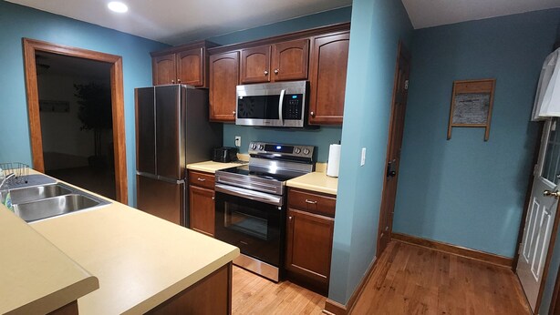 A kitchen with wooden cabinets, a stainless steel refrigerator, a microwave, and an oven.