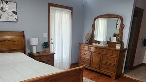 A bedroom with a wooden bed, a dresser, a mirror, and a ceiling fan.