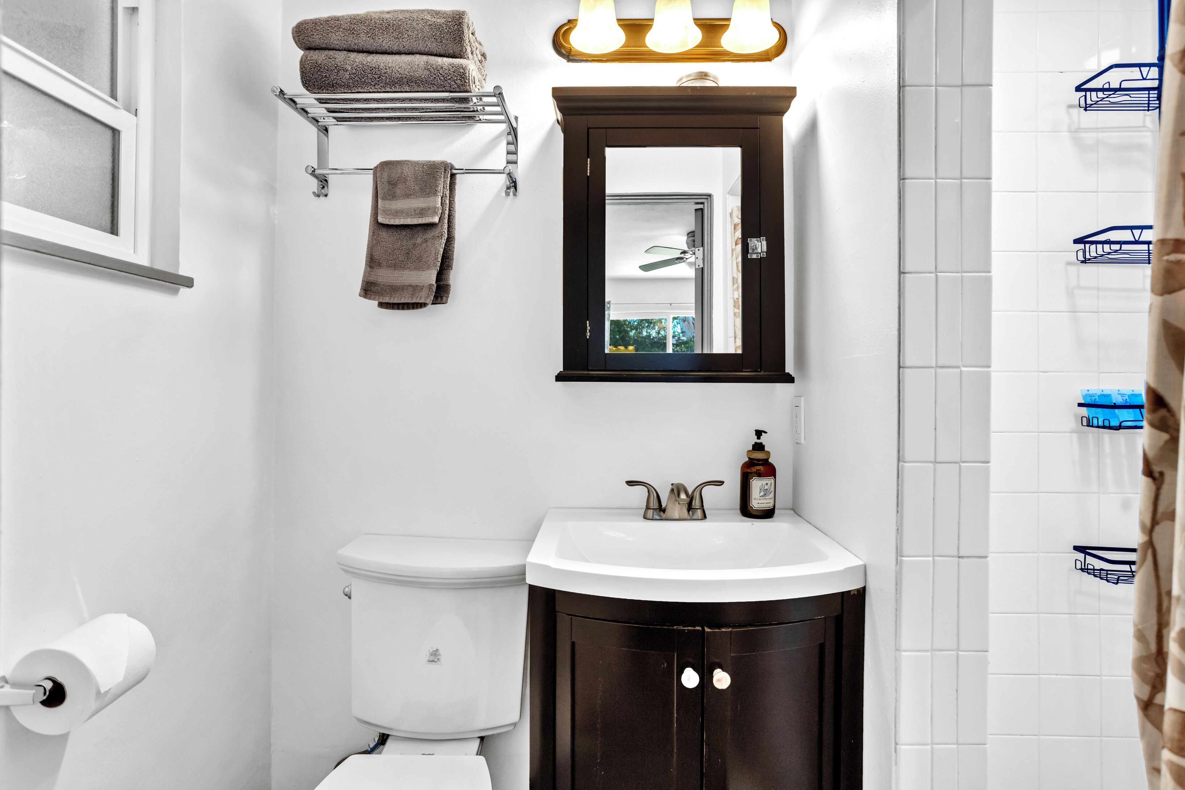 Un bagno con toilette, lavandino, specchio, porta asciugamani e tenda della doccia.