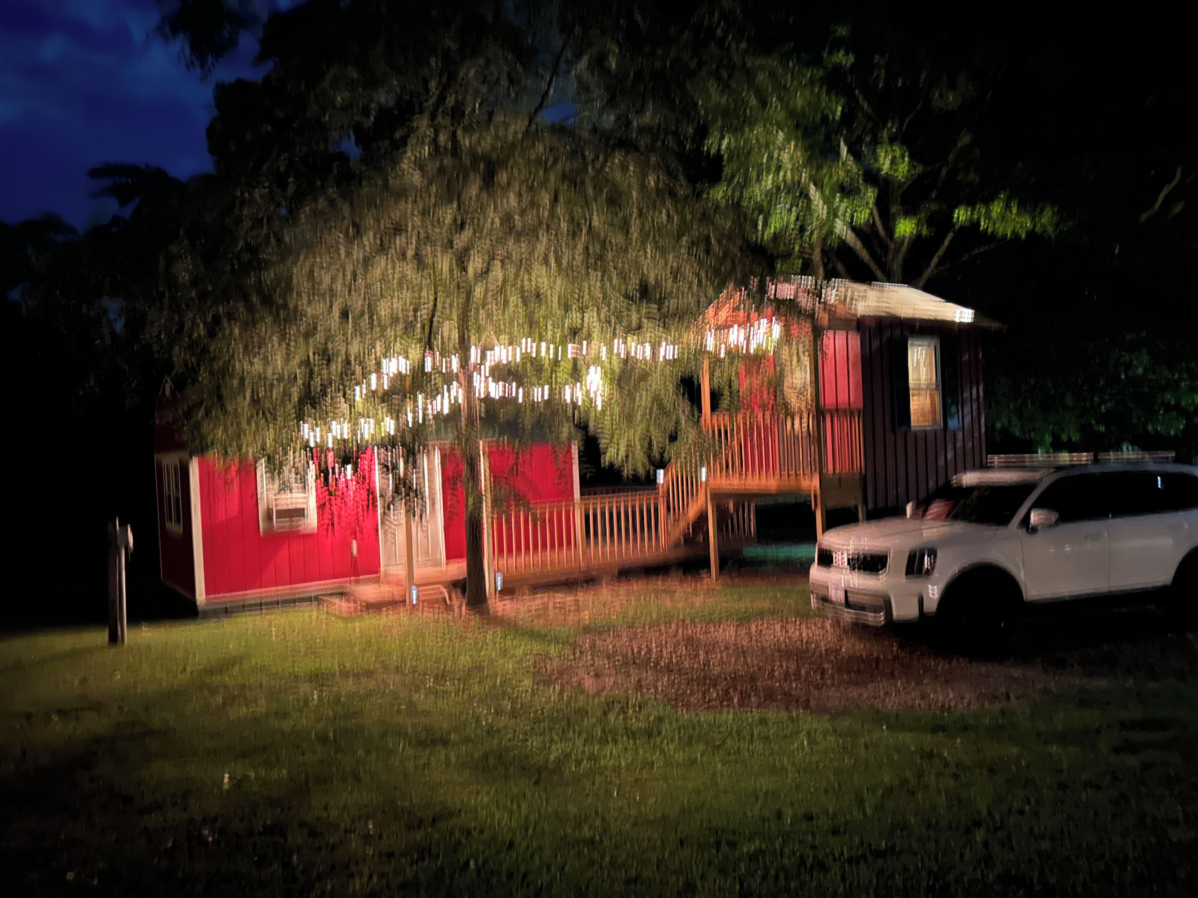 A house with a red exterior, a porch, and a car parked in front.
