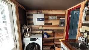 Une cuisine compacte équipée d’un lave-linge, d’un four encastré et d’un panneau mural en bois.