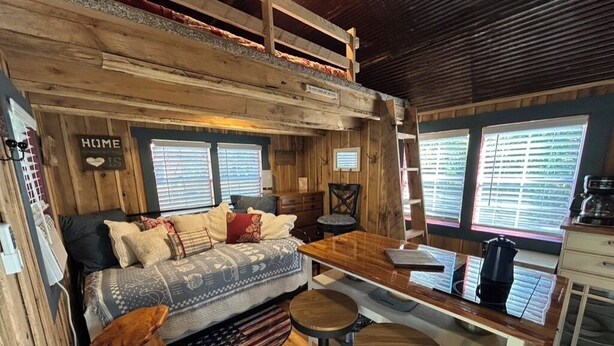 Une pièce confortable, aménagée comme un chalet, avec un intérieur en bois, un canapé, une table à manger et un coin cuisine.
