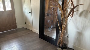 A hallway with a large mirror, a vase with dried plants, and a wooden door. - The Loyola – Warm & Welcoming Home Base for Your Pueblo Adventure (Pueblo)