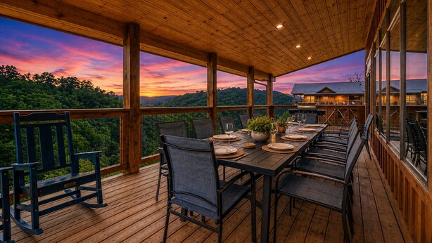 Une terrasse extérieure avec une table à manger pour six personnes, entourée de chaises, donnant sur un paysage boisé.