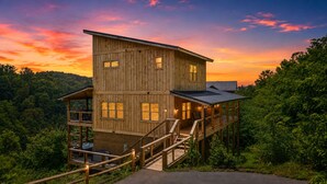 Une cabane en bois à plusieurs niveaux, dotée d’un balcon et d’un escalier.
