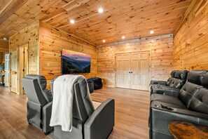A wooden cabin interior with a massage chair, a massage table, and a leather sofa.