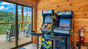 Une cabane en bois équipée de deux bornes d’arcade, de fauteuils à bascule et d’un extincteur.