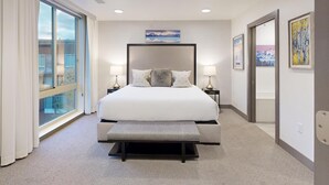 A modern hotel room with a large bed, two bedside tables with lamps, a bench, a large window with curtains, and artwork on the walls. - Bella's Mountain Vista | Prime Walk-to-Town 1BR Condo in Jackson Hole (Jackson)