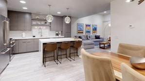 A modern kitchen with a central island, bar stools, and pendant lighting. - Bella's Mountain Vista | Prime Walk-to-Town 1BR Condo in Jackson Hole (Jackson)