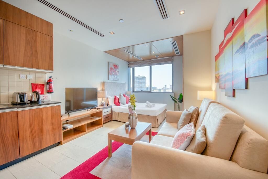 A modern living room with a sofa, TV, and kitchen area.