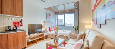 A modern living room with a sofa, TV, and kitchen area.