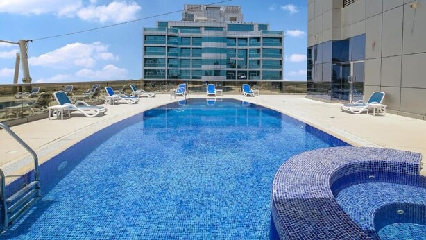 Ein Schwimmbecken mit Liegestühlen und einem modernen Gebäude im Hintergrund.