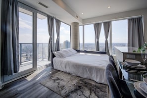 Une chambre d’hôtel moderne dotée d’un grand lit, d’un coin repas et offrant une vue sur la ville.
