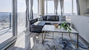 A modern living room with a sectional sofa, a coffee table, and a city view.