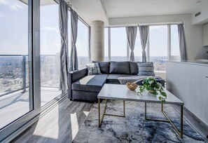 Un salon moderne avec un canapé d’angle, une table basse et une vue sur la ville.